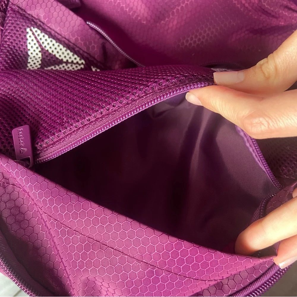 Purple Reebok book bag with tear right near strap